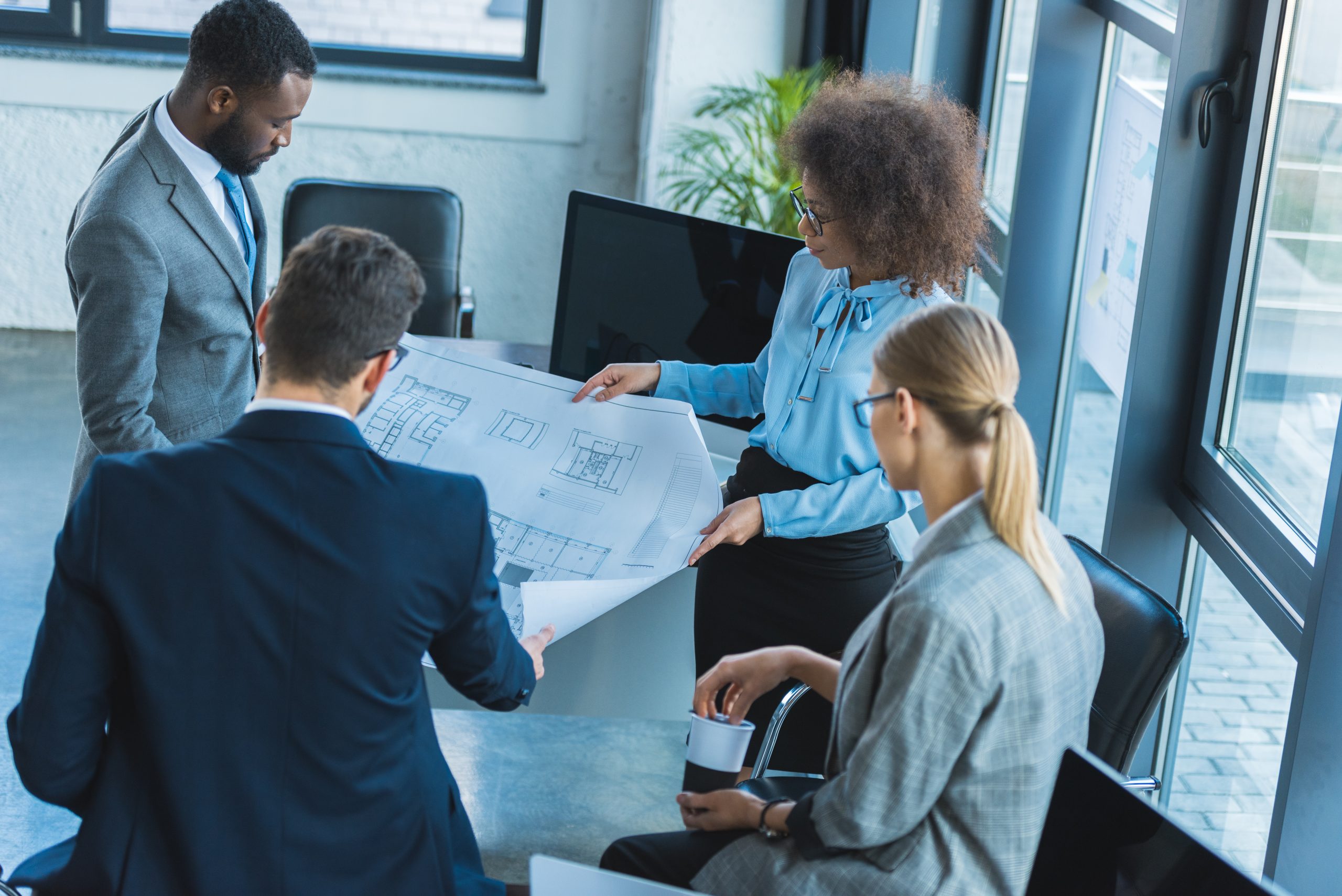High angle view of multicultural businesspeople looking at blueprint in office
